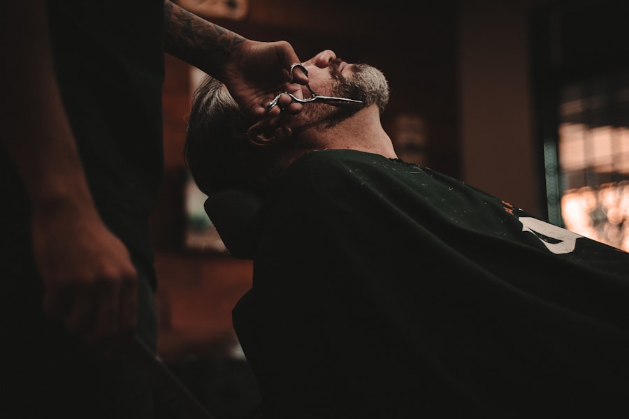 A barber trimming a client's beard in a dimly lit barbershop chair